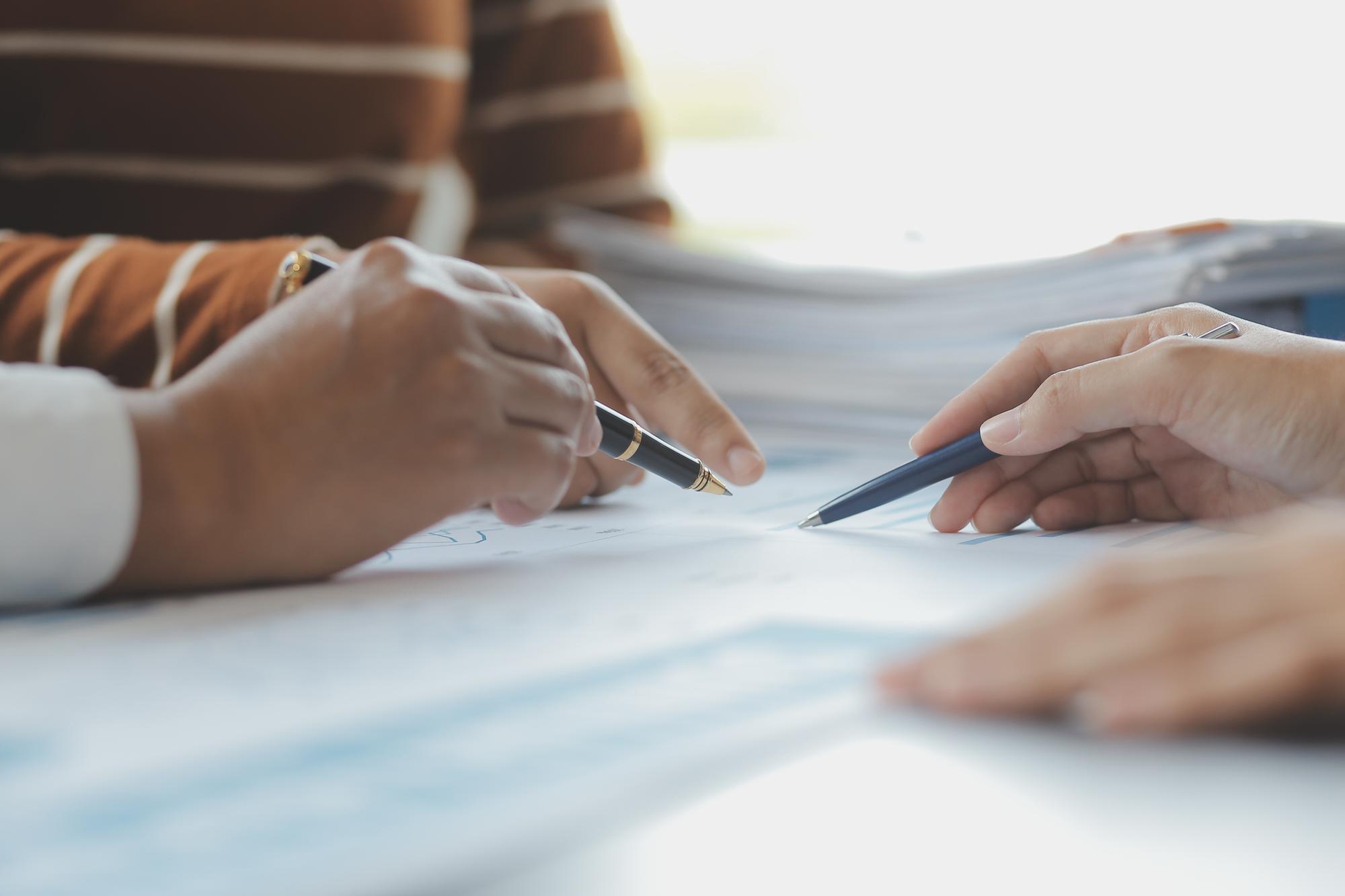 Close up of hands signing financial documents